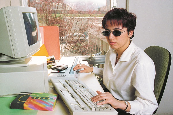 Una joven ciega en su puesto de trabajo con un ordenador y línea braille