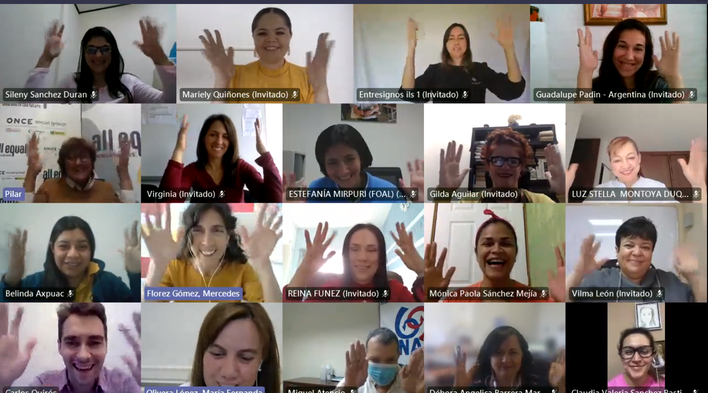 Imagen de la sesión de cierre de la actividad, en la que los participantes aparecen con las manos en lo alto, haciendo el signo de aplauso en lengua de signos