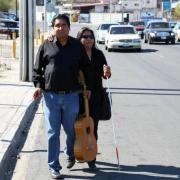 Dos personas ciegas caminan por el arcen de una carretera