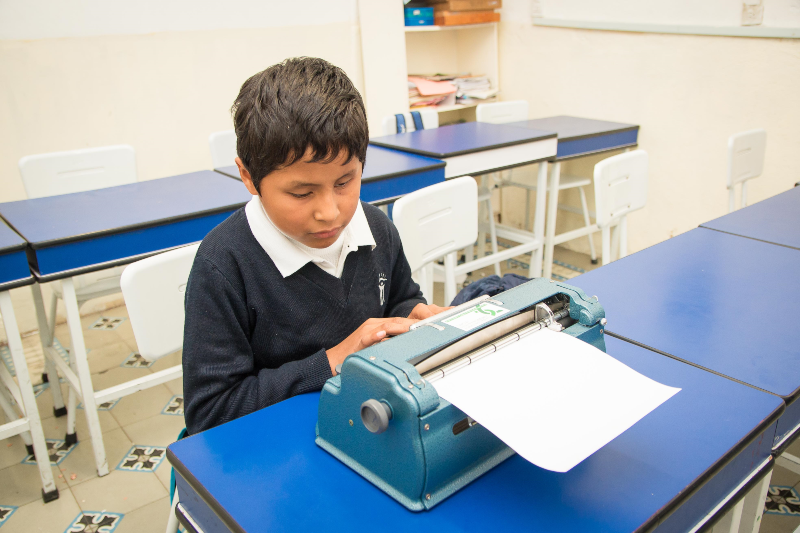 Niño mexicano escribe con máquina Perkins