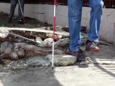 Una persona con disacpacidad visual transita por un terreno con baches