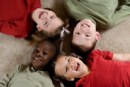 Cuatro niños tumbados de espalda en una alfombra juntando sus cabezas