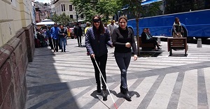 Una persona ciega camina por la calle con un acompañaante