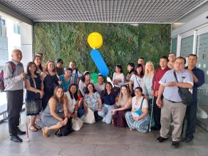 Fotografía muestra a los participantes en la entrada del SBO de la ONCE en Madrid, detrás de ellos está ONCELIO el símbolo de la ONCE